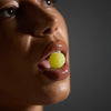 Close-up of a person holding a yellow gummy near their mouth against a dark background