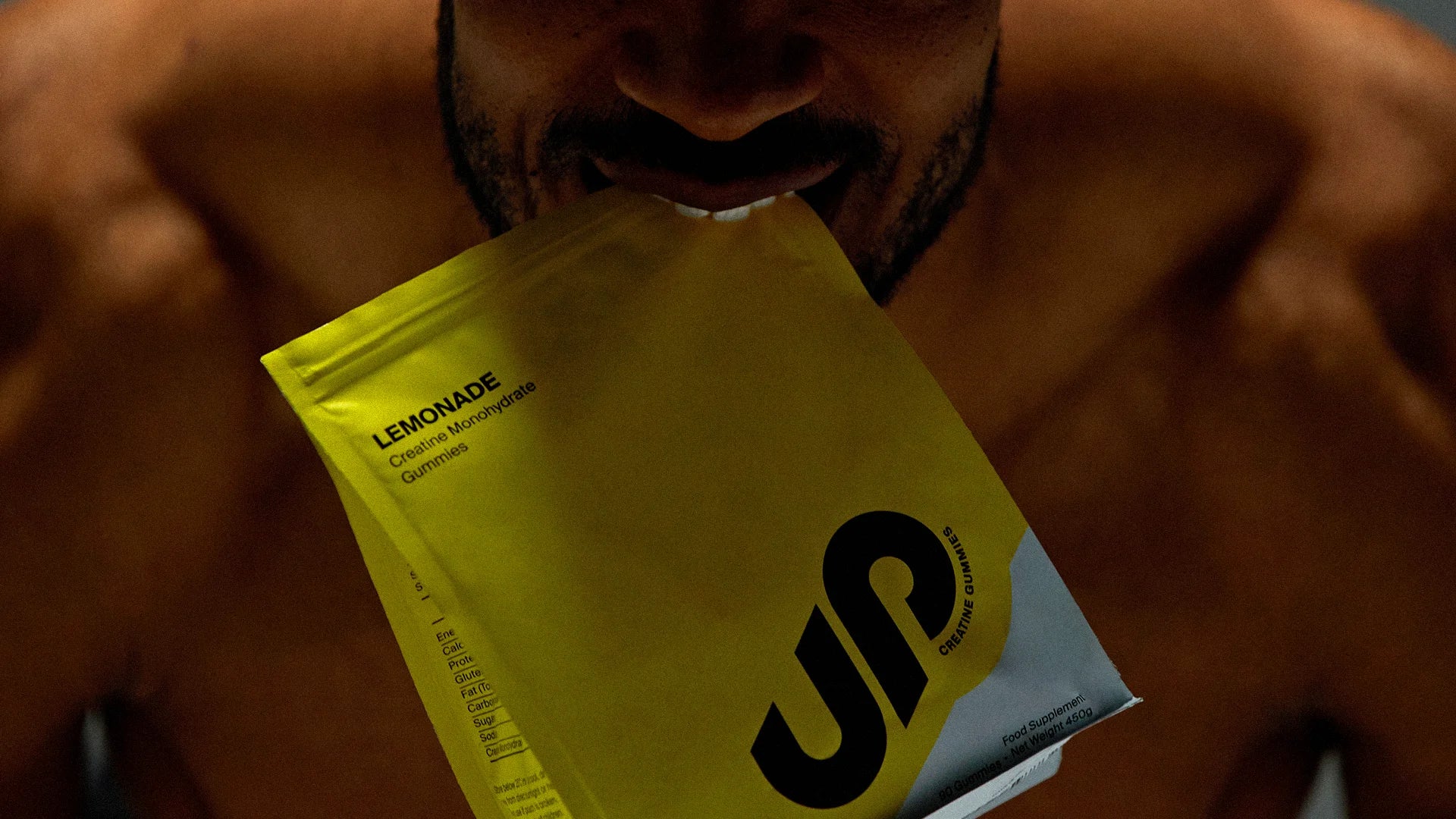 Person holding a yellow creatine gummies packet with a brand logo.