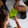 Person holding a green supplement package with 'UP' branding, sitting on a white surface.