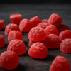 Red gummy candies on a dark surface